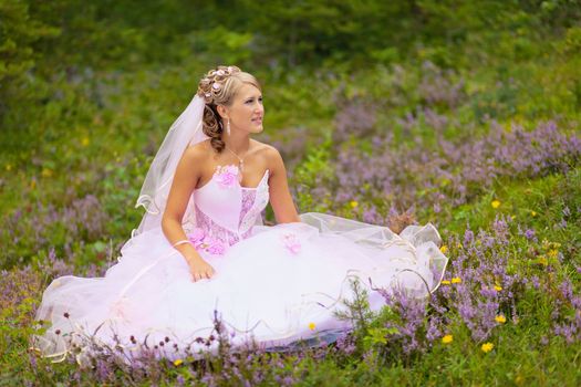A beautiful young bride is sitting alone in the woods