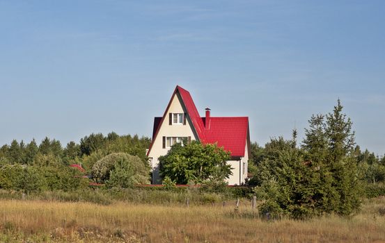 New country house with red roof among trees