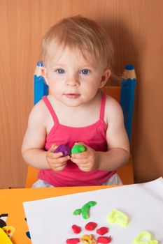 Baby girl molding from plasticine at table