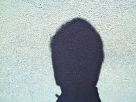 shadow of a head on a pale blue wall