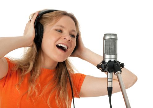 Young woman in orange t-shirt singing with studio microphone. Isolated on white background.