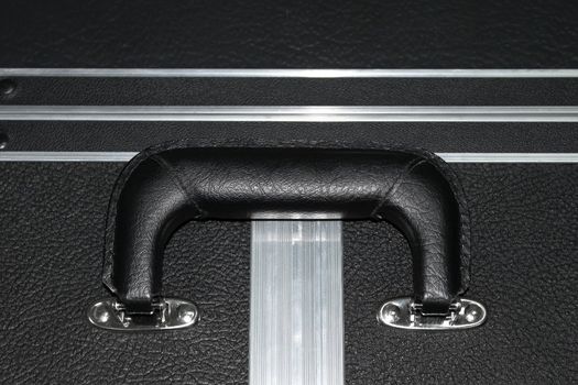 Fragment of a large suitcase with black artificial leather with a handle and aluminium edges of rigidity