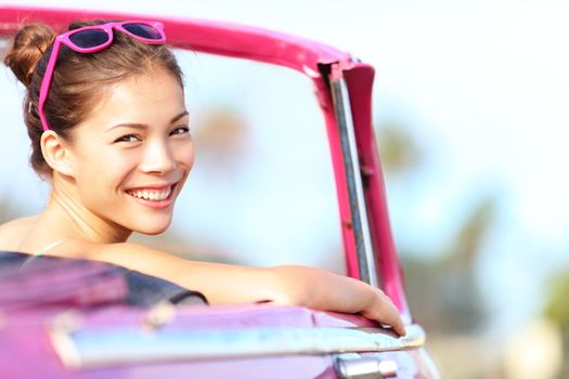 Car woman happy in old pink retro vintage car. Young woman driving on road trip on beautiful sunny summer day. Pretty mixed race Asian / Caucasian female model.