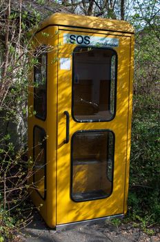 Old fashioned German phone booth surrounded by bushes
