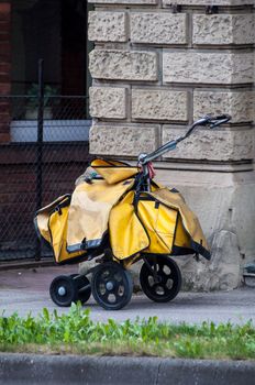 Postman cart heavily loaded with yellow bags for home delivery