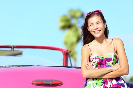 Car woman happy smiling by pink vintage car. Beautiful young multiracial female driver in Havana, Cuba.