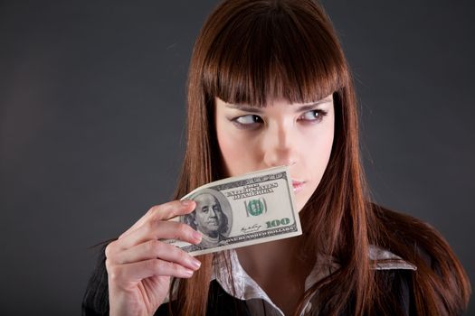 Serious looking businesswoman with dollars, studio shot 