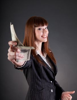 Smiling business woman with dollars offering credit, studio shot 