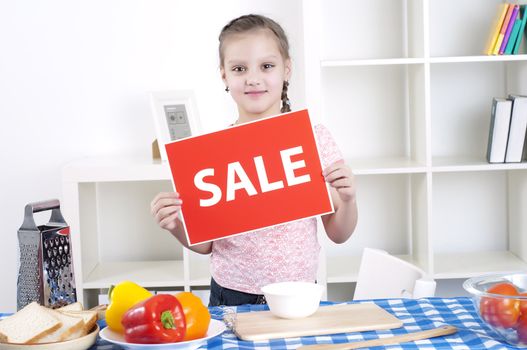 Young child cooking fresh meal at home and holding sale sign