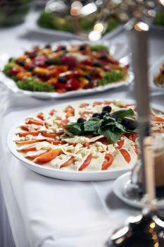 Platter of mozzarella cheese and tomato arranged in a decorative alternating pattern on a buffet table at a catered event or wedding reception