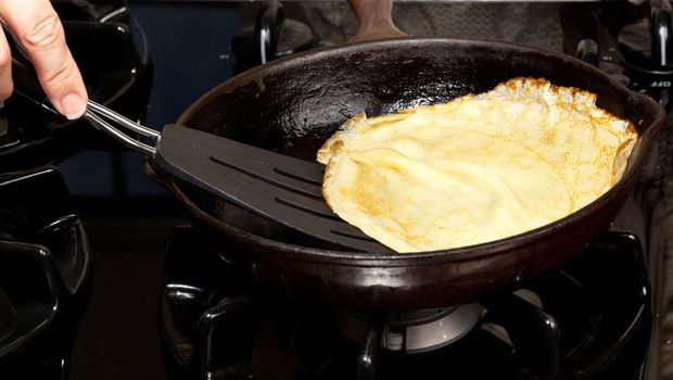 Frying pan on gas stove with pancake mixture being cooked