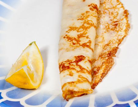 Cooked homemade pancake and lemon on blue plate