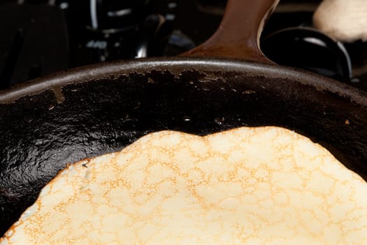 Frying pan on gas stove with pancake mixture being cooked