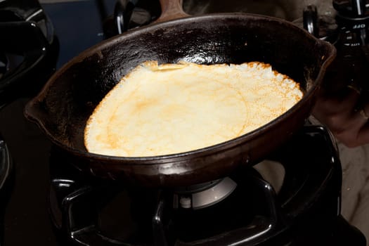 Frying pan on gas stove with pancake mixture being cooked