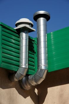 Pipes of ventilation are located on a wall of a building