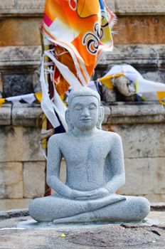 Buddha stone statue in meditation pose with religious flag on background