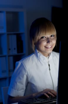 beautiful young woman doctor working at night in the office, smiling