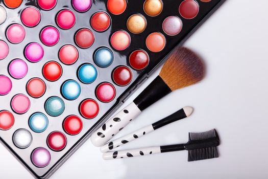 Colorful lip gloss palette with set of brushes, studio shot on white background 