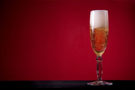 Champagne glass over red background, lot of copy-space 