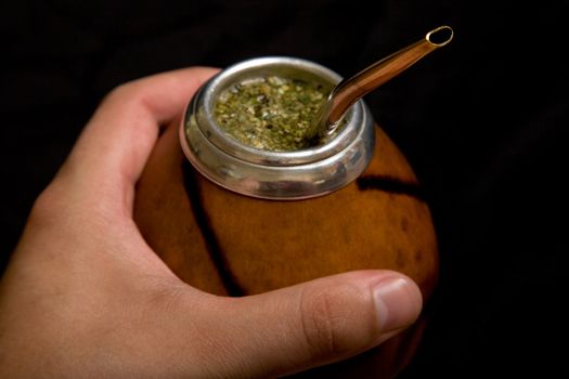 Male hand holding Argentinean Calabash with Bombilla, selective focus 