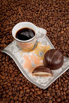 Coffee cup with candies on beans background, high angle view 