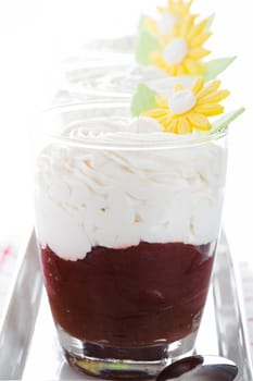 A glass with mousse au chocolat and whipped cream on white background as a studio shot