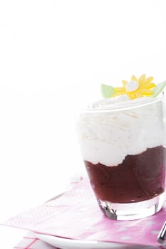 A glass with mousse au chocolat and whipped cream on white background as a studio shot