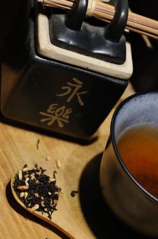 Asian black tea set with rice grains over wood background
