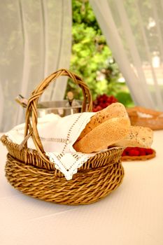 Table setting with bread basket outdoors with wine bottles on background