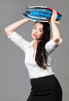 Portrait of a tired and overworked business woman carrying paperwork on her head