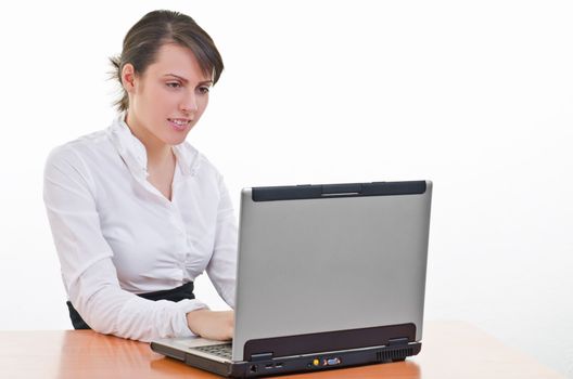 Young business woman sitting at desk and typing on laptop, high key, focus on eyes