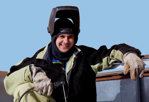 Welder in a special suit against the blue sky