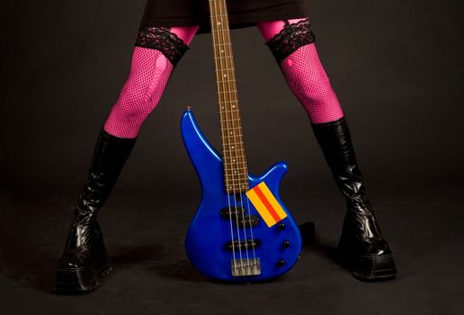 Close-up of woman legs with bass guitar isolated in studio