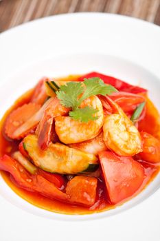 Thai style sweet and sour shrimp dish presented beautifully on a round white plate.