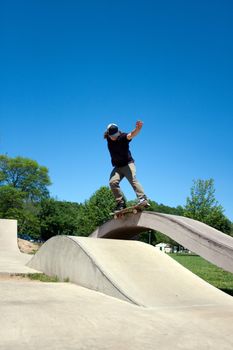 Action shot of a skateboarder performing a grind at a concrete skate park.