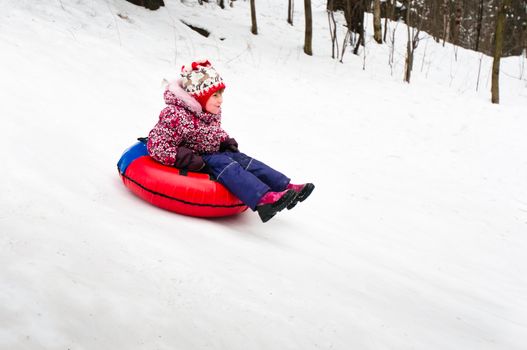Child on inflatable sleds riding down from slope