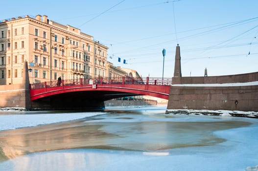 Small red bridge and frozen channel in Saint-Petersburg, Russia