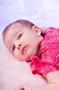 View of a newborn baby on a smooth bed.