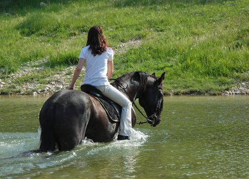 young woman and her black stallion in a river