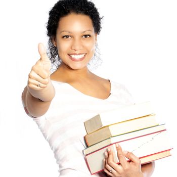 Beautiful smiling vivacious African American woman carrying a pile of textbooks giving a thumbs up of approval and success isolated on white