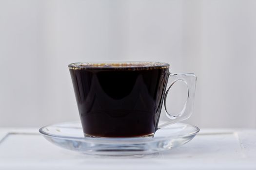 A clear coffee cup filled to the brim with black coffee.