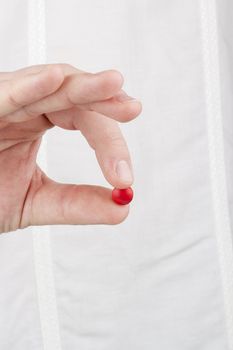 Close-up photograph of a hand holding a red tablet.