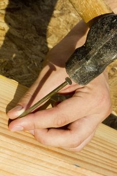 Construction worker hammering a nail into a piece of wood.