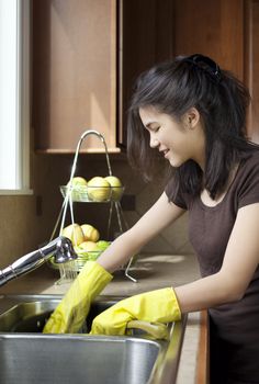 Teen girl washing dishes at kitchen sink