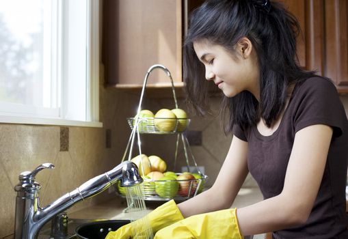 Teen girl washing dishes at kitchen sink