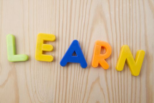 Letter magnets LEARN closuep on wood background