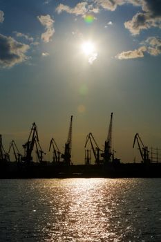 Silhouettes of harbor cranes over blue sky background 