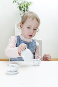 Cute little girl drinks tea at home.