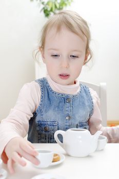 Cute little girl drinks tea with bagel