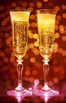 Two champagne glasses over holiday bokeh background 